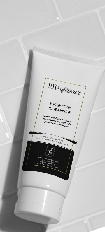 Everyday cleanser tube on a white tiled background, featuring exfoliating enzymes and green tea extract.