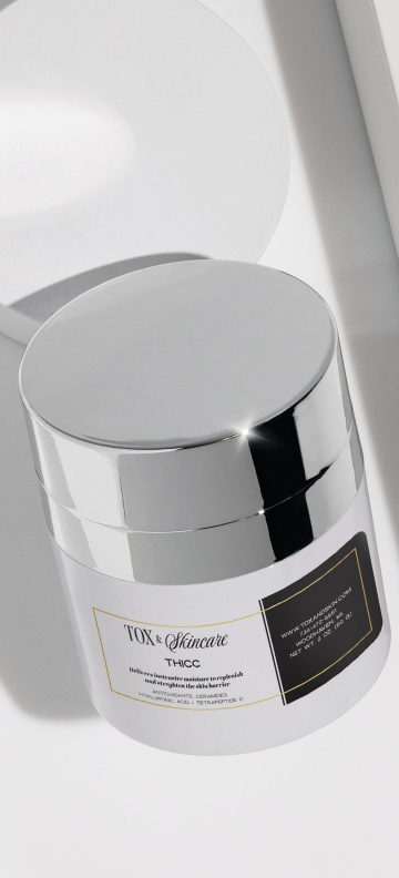 Silver-lidded TOX Skincare THICC moisturizer jar against a white background.