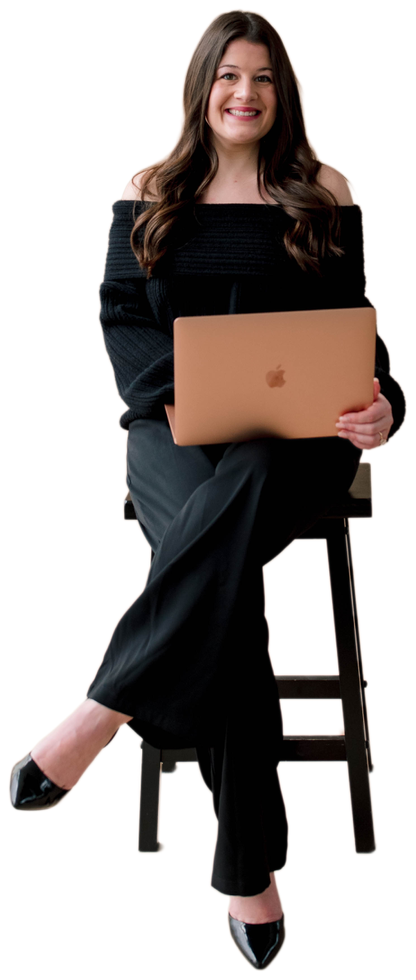 Woman in black outfit sitting on stool with laptop smiling.