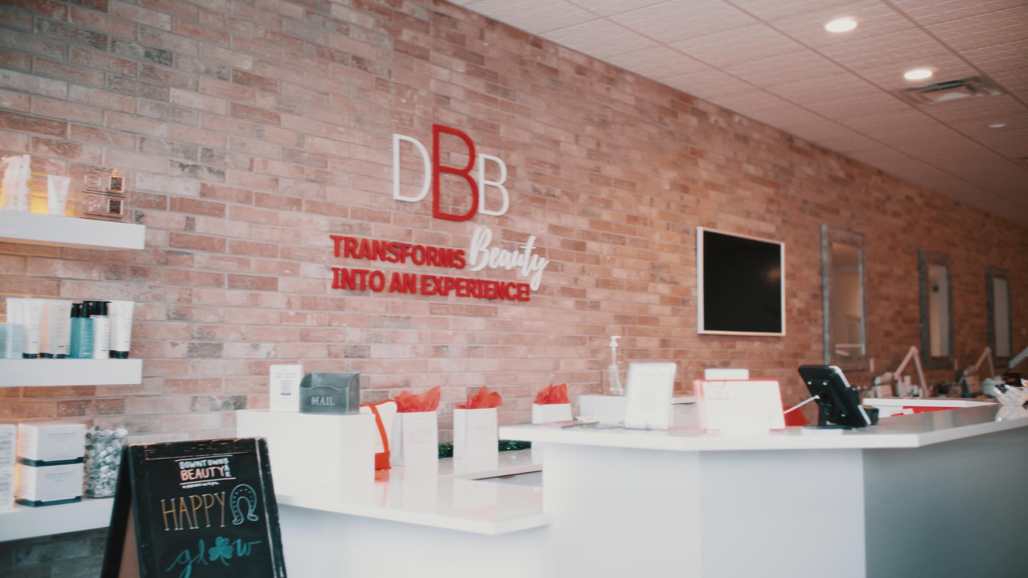 Beauty salon reception with brick wall and product display, featuring the text Transforms Beauty into an Experience.